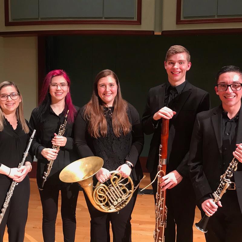 students standing on stage holidng wind instruments